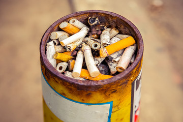 Ashtray at the smoking place, full of the variety of cigarettes after smoked.