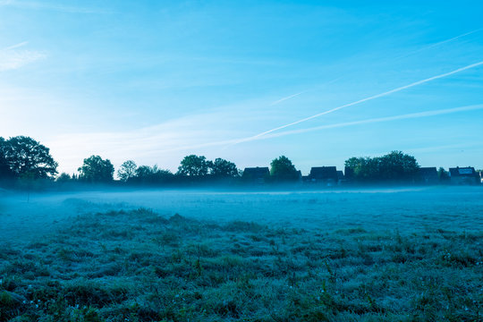 Nebelschwaden am frühen Morgen mit Dorf im Hintergrund. - Standort: Deutschland, Nordrhein - Westfalen, Borken
