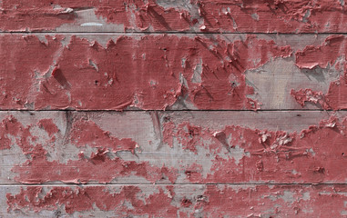 wall of old wooden boards with peeling red paint