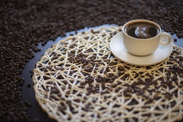 Cup of coffee with coffee beans on wooden background.