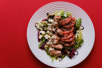 Meat salad with tomato served in white plate on dark table. Copy space