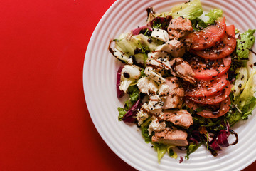 Meat salad with tomato served in white plate on dark table. Copy space