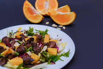 Meat salad with tomato served in white plate on dark table. Copy space