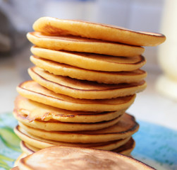 Big stack of delicious pancakes is on a blue plate
