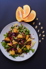 Meat salad with tomato served in white plate on dark table. Copy space