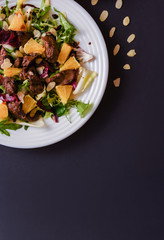 Meat salad with tomato served in white plate on dark table. Copy space