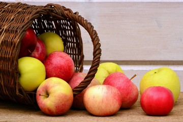 Fresh ripe juicy apples in basket on wooden table on white background.