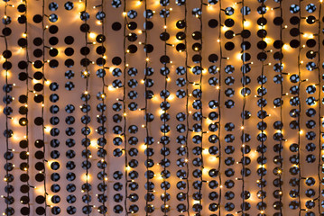 Christmas lights of garland on a metal grill with circles, cream color, background