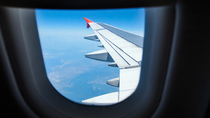 Fototapeta na wymiar View through the illuminator on airplane wing flying in the sky