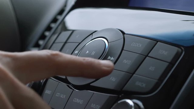 Male finger pressing radio button on car control panel