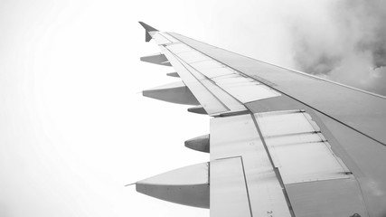 Black and white image of airplane flying through clods