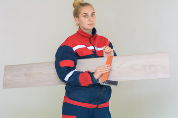 Happy young woman measuring and marking laminate floor tile, installing laminate flooring. Close-up...