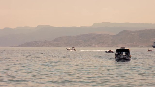 The Gulf of Aqaba, Jordan. Glass boat and a speed boat in the red sea with Mounties background .4K