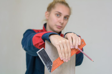 Happy young woman measuring and marking laminate floor tile, installing laminate flooring. Close-up...