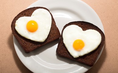 Two Slices of Bread with Fried Eggs in the Shape of Heart on the