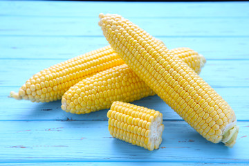 Fresh corn on cobs on a blue wooden table, closeup