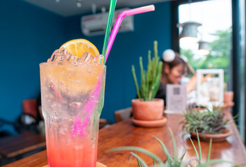 Red punch soda drink with orange silce on the glass with person relax in the background with copy space