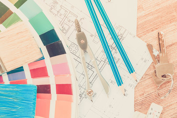 Interior designer's working desktop with architectural plan of the house, keys, color palette and brushes retro toned