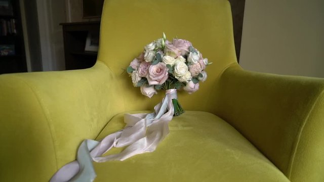 Wedding bridal bouquet of pink and white roses lying on yellow chair