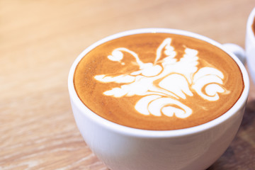 close up a cup of coffee with milk latte art serve on the wooden table in the vintage style cafe