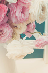 Pink and white ranunculus flowers bouquet in vase close up, retro toned