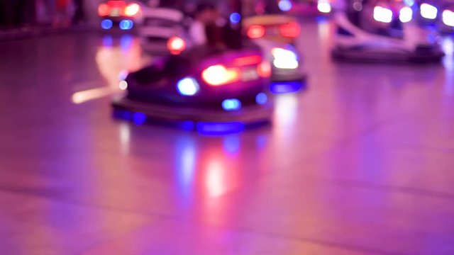 Silhouette of unrecognizable girls driving bumper car attraction nighttime view of funny atmosphere at the amusement park 4K UHD cinematic camera used