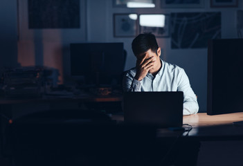 Exhausted Asian businessman working late at night in an office
