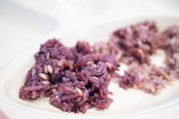 Close up of freshly cooked purple or black rice on a white plate. High in nutrients and good source of vitamin, mineral, antioxidant, anthocyanin, high in fiber. Healthy eating and eat well concept.