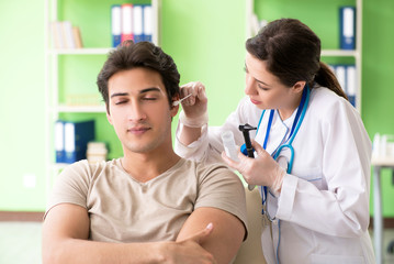 Female doctor checking patient's ear during medical examination 