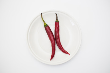 Top view of Red hot Peppers on white plate over white background