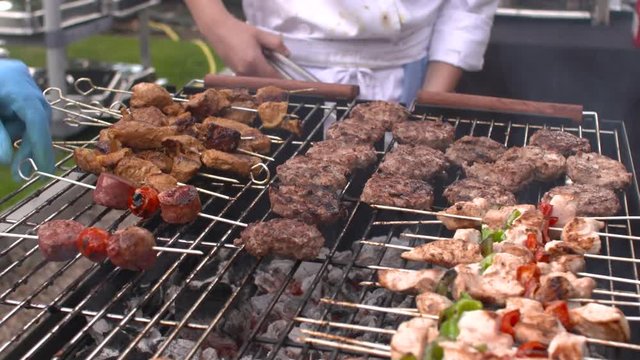 Chicken, Lamb, Beef and burgers being cooked and turned on a large BBQ