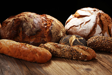 Different kinds of bread and bread rolls on board from above. Kitchen or bakery