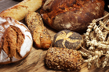 Different kinds of bread and bread rolls on board from above. Kitchen or bakery