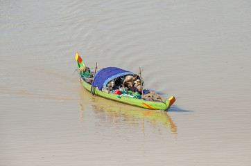 Long-tail wooden boat with a Cambodian family living on it on the Mekong River