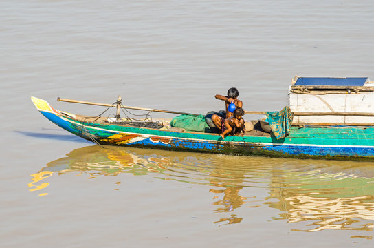 Long-tail wooden boat with a Cambodian family living on it on the Mekong River