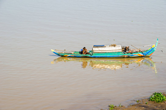 Long-tail wooden boat with a Cambodian family living on it on the Mekong River