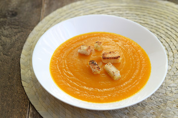 pumpkin soup in a white plate with garlic croutons