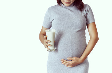 Asian women holding a glass of milk and holding her pregnant,.mode of happiness.Focus on hands