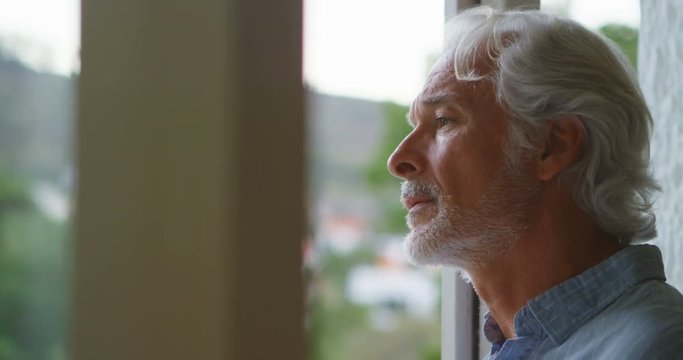 Upset senior man looking through window 4k