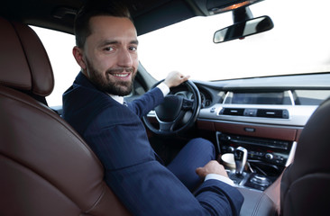 businessman sitting at the wheel of a prestigious car
