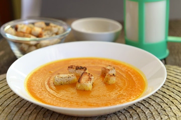 Pumpkin soup in a white plate with croutons