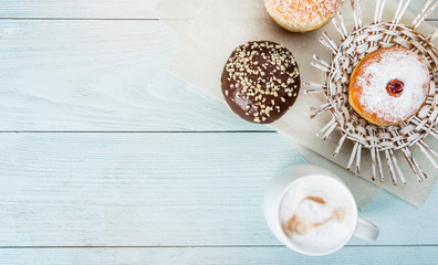 Hot coffee latte and delicious and glazed pastries on a blue wooden background, top view