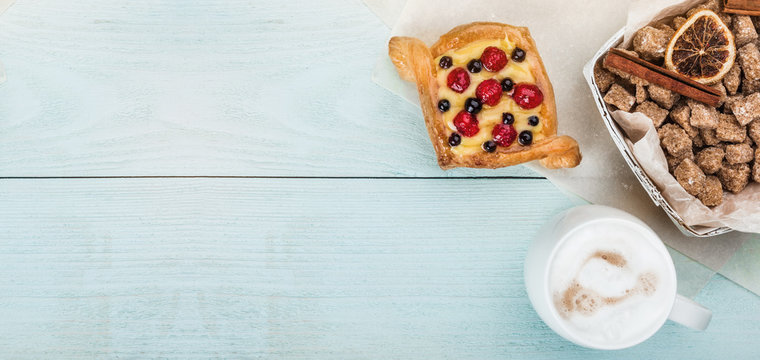 Delicious pastry with berries and cream for breakfast on wooden blue background, top view