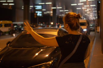 Woman hailing for cab at night in an airport.