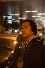 Asian man waiting for his car ride at night in an airport.