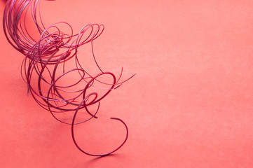 A bunch of red-colored curly and wavy sticks from the upper left hand corner set on a plain red background in horizontal format.