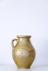 Empty vase standing in front of white wall.