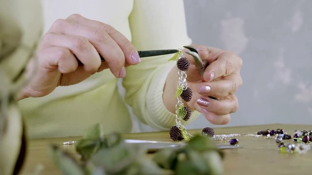 The young woman creating handmade jewelry bracelet in the studio. 4K