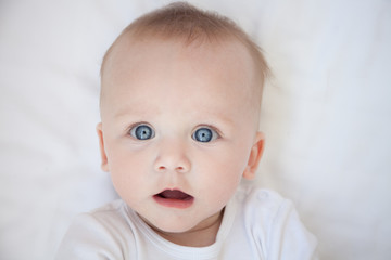 surprised child lies on his back on a white sheet
