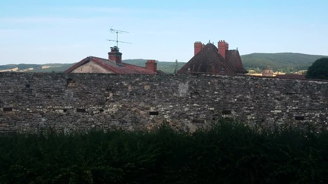 Revealing shot over the wall in small town Cluny in France. A beautiful sight in the background.